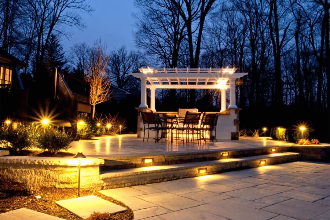 Patio and backyard area with installed landscape lighting allowing extended nighttime outdoor use
